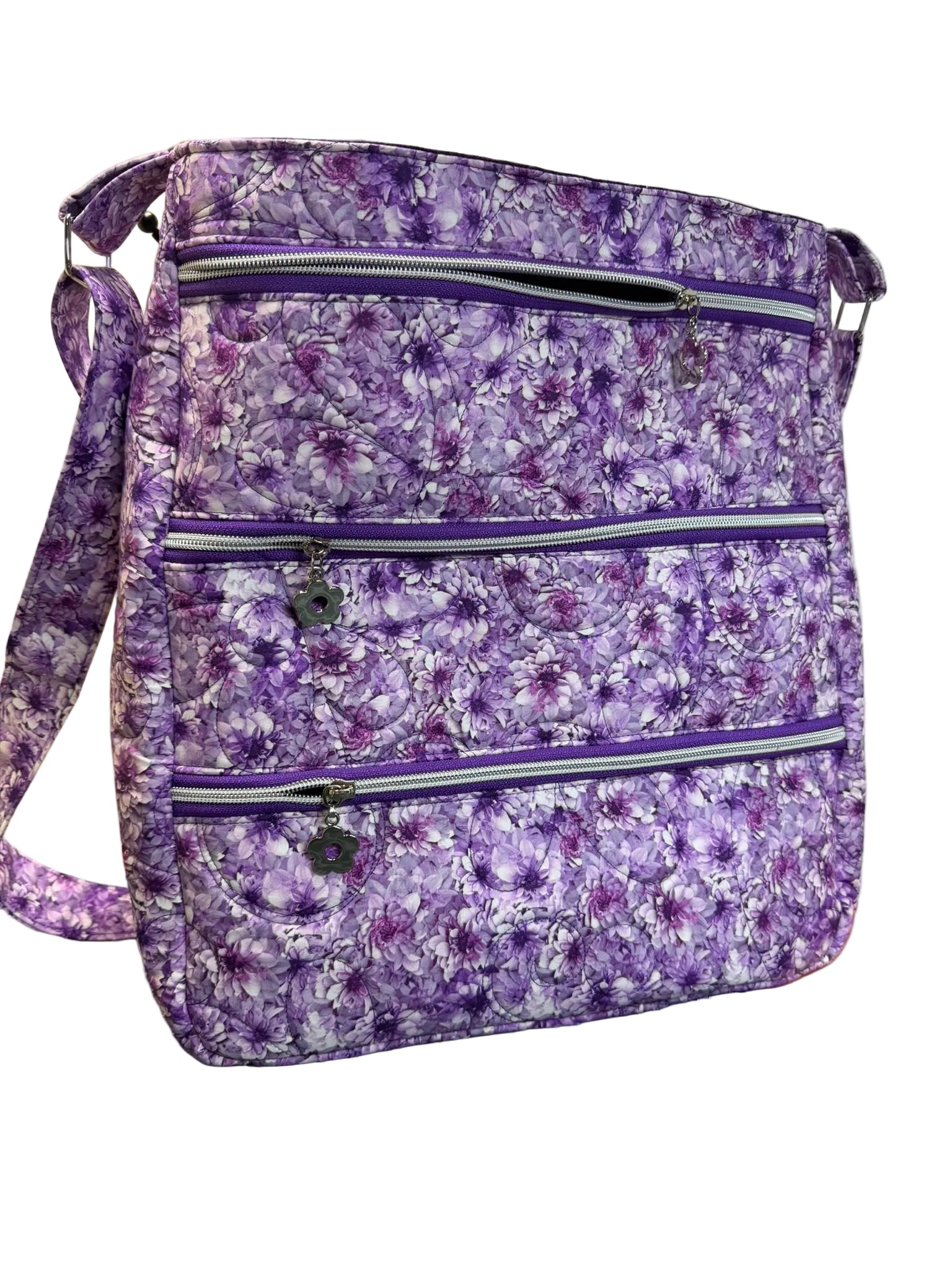 A purple floral print crossbody bag with multiple zippered compartments.